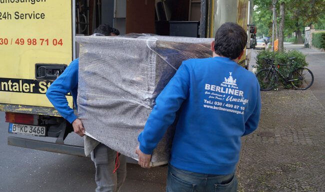 Umzugshelfer tragen vorsichtig Schrank