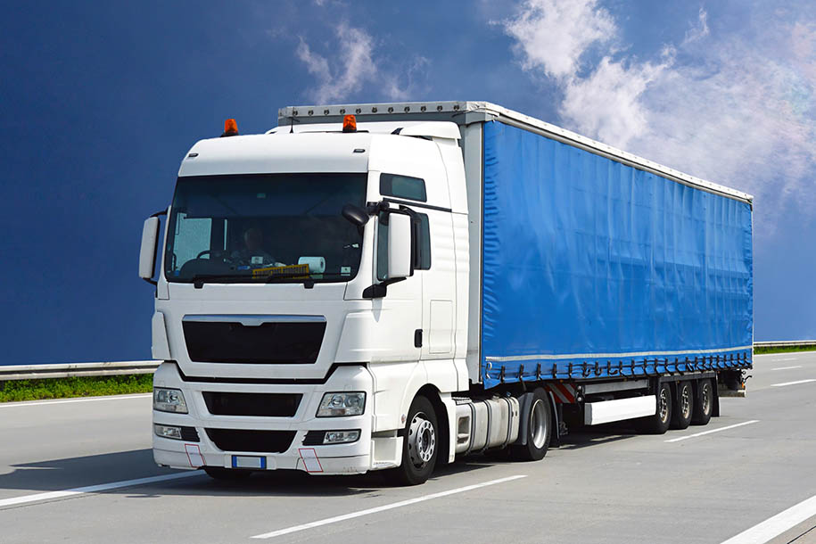 Ein weißer LKW fährt unter blauem Himmel auf einer Autobahn – Berliner Umzüge